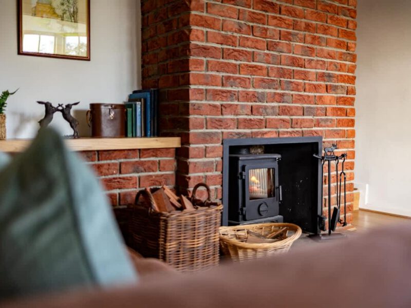 Cozy fireplace with wood baskets at Yew Tree Cottage farm stay.