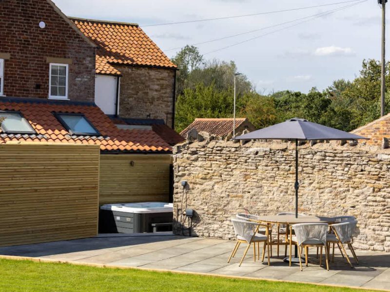 Castle View Cottage: patio with hot tub, dining area, and EV charger.
