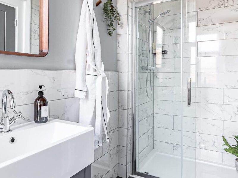 Modern bathroom with marble tiles and a plush robe at Crescent View holiday let.