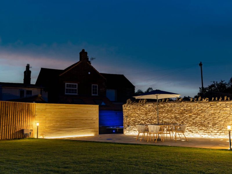 Castle View Cottage: illuminated garden patio with hot tub and dining area.