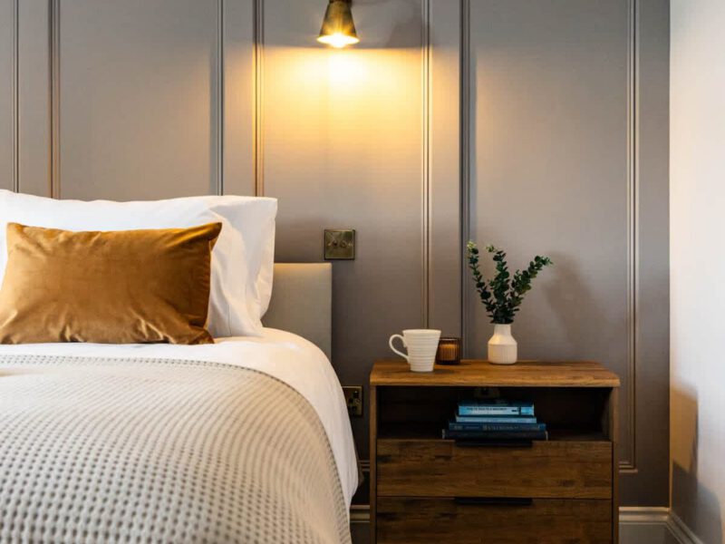 Comfortable bedroom with bedside table and slippers at Castle View Cottage.