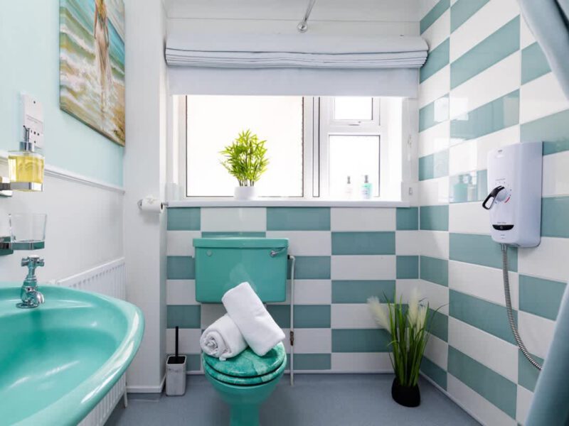 Coastal Village Hideaway bathroom with teal sink and toilet.