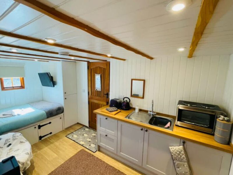 Cosy Shepherd's Hut interior with compact kitchen and sleeping area.