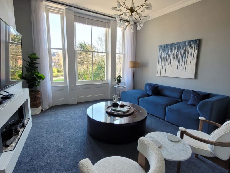 Crescent View living room with blue sofa and large windows.
