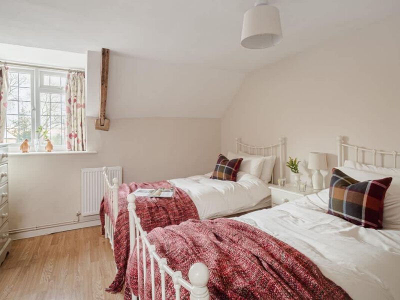 Twin beds with cozy throws in Garth Cottage, a dog-friendly holiday let.