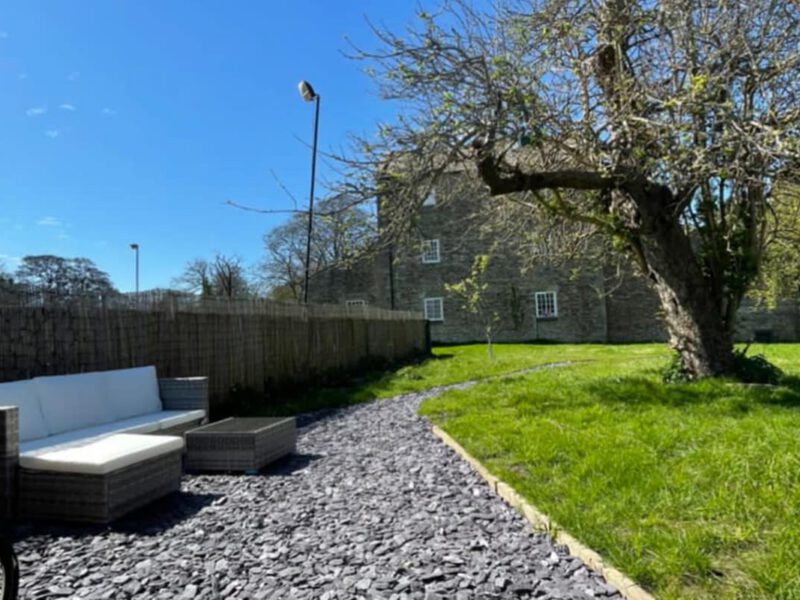 Cosy outdoor seating area at Shepherd's Hut farm stay with stone building.