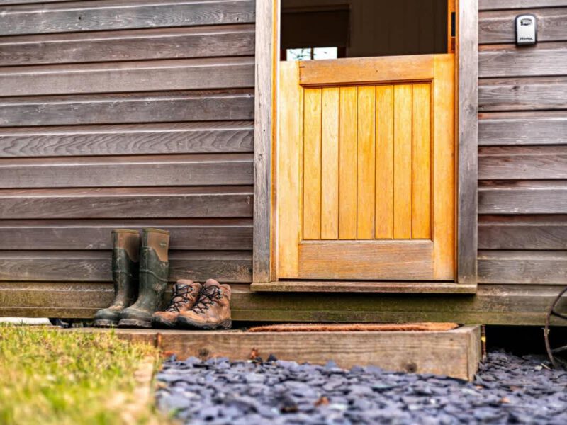 Shepherd's Hut cosy farm stay entrance with boots and wooden door.