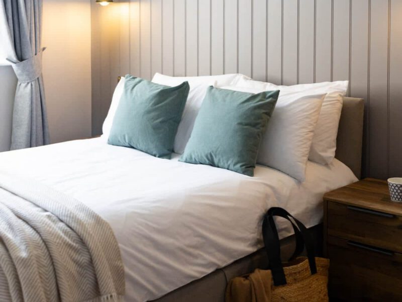 Comfortable double bed with teal cushions at Castle View Cottage.