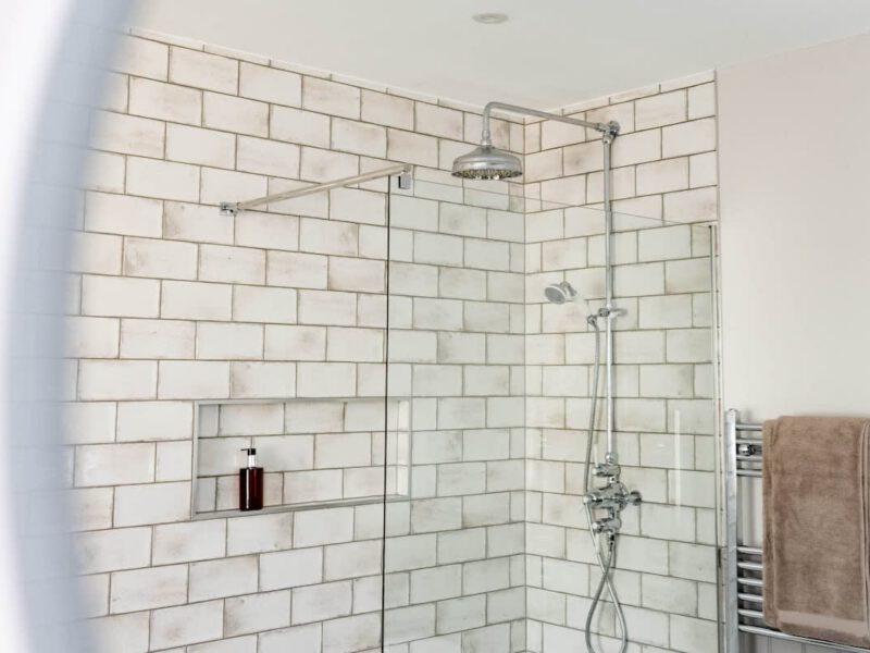 Modern shower with subway tile and chrome fixtures at Castle View Cottage.