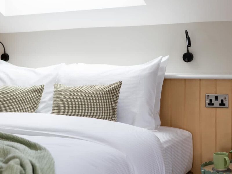Comfortable double bed with patterned cushions at Ivy Mews barn.