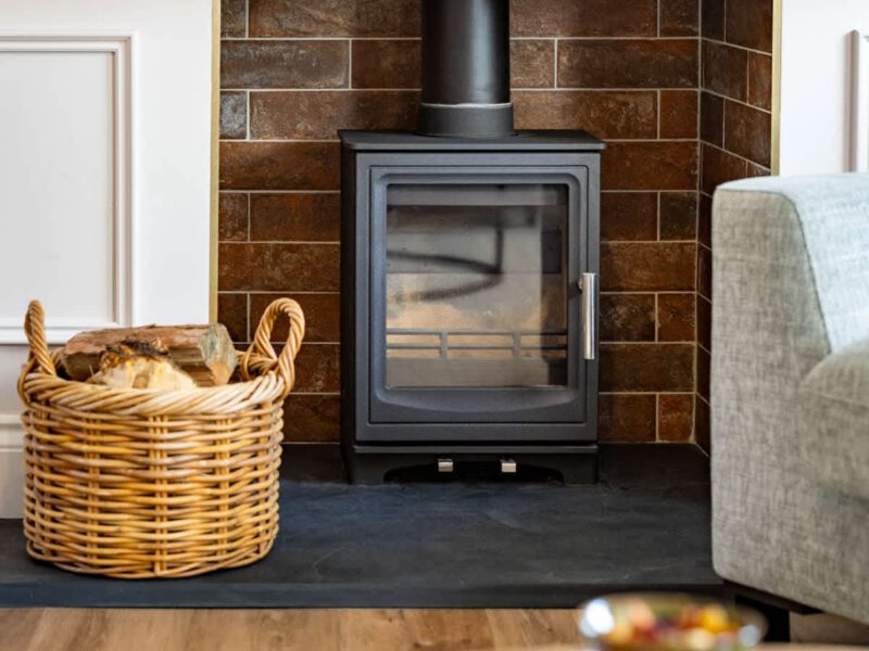 Wood-burning stove and log basket in the living area of Castle View Cottage.