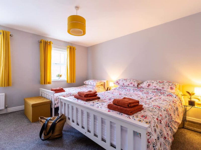 Townhouse Harbour Retreat bedroom with two beds and yellow curtains.