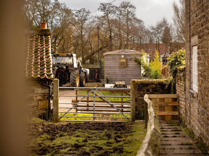 Shepherd's Hut farm stay with tractor and rustic shed.