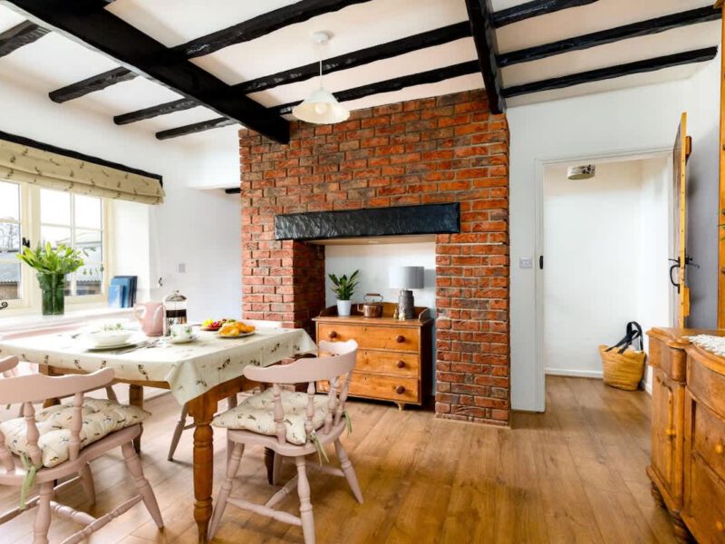 Cosy dining area with brick fireplace at Yew Tree Cottage farm stay.