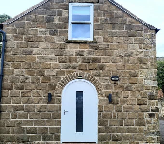 Ivy Mews barn exterior with arched doorway and stone facade.