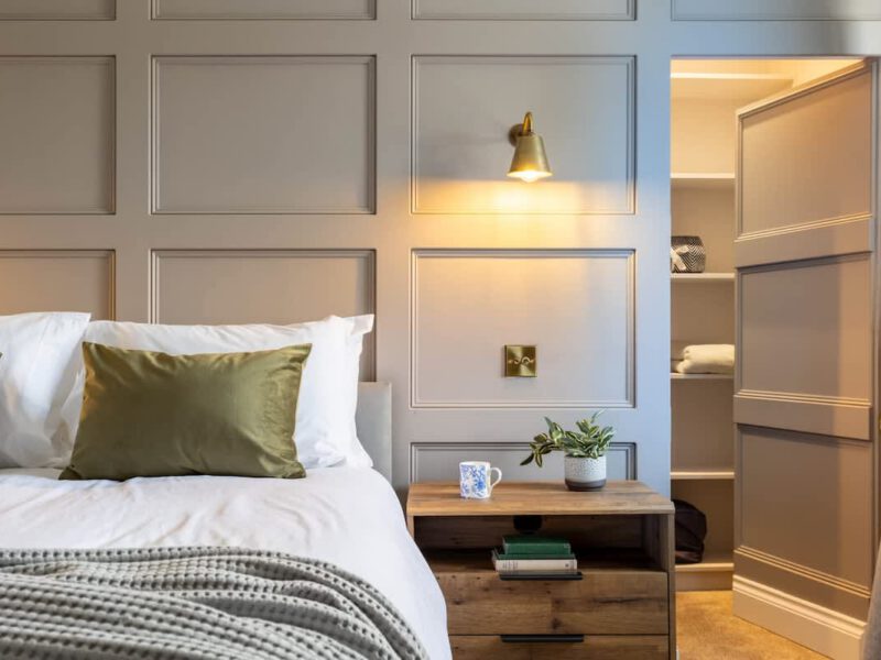 Stylish bedroom with bedside table and open wardrobe at Castle View Cottage.