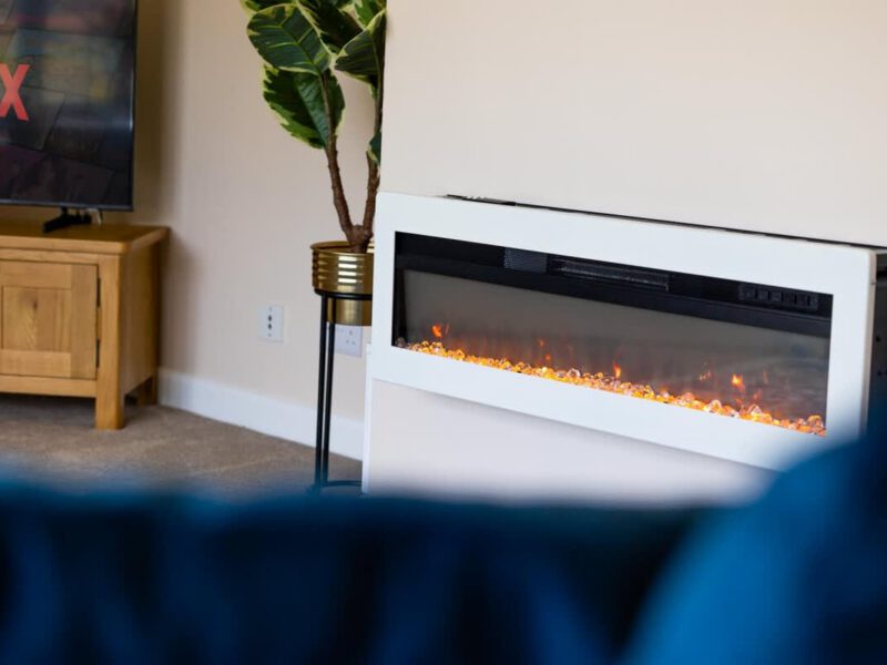 Modern electric fireplace with ambient lighting at Coastal Village Hideaway.