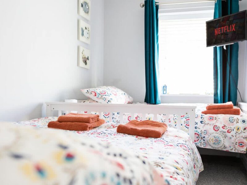 Twin beds with colourful bedding and Netflix TV in Townhouse Harbour Retreat.