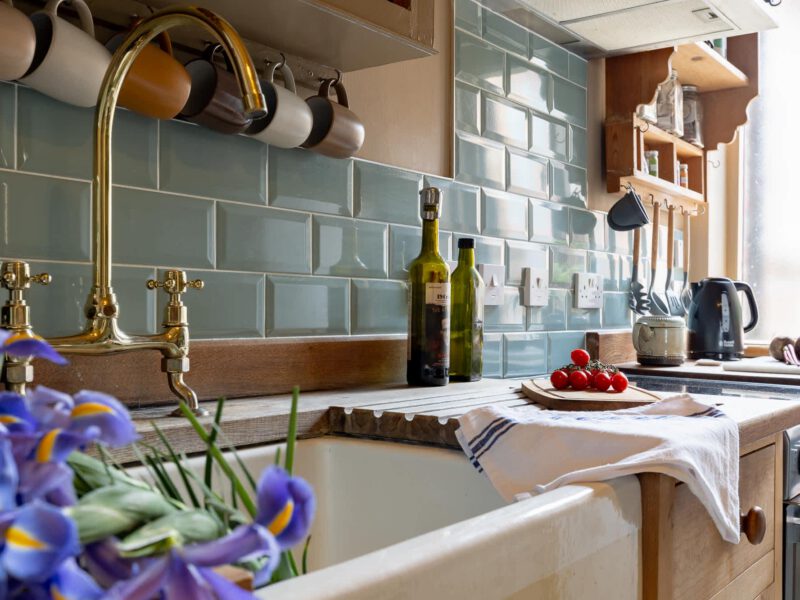 Stylish kitchen sink area with brass tap and blue tiles at The Loft by the Bay.