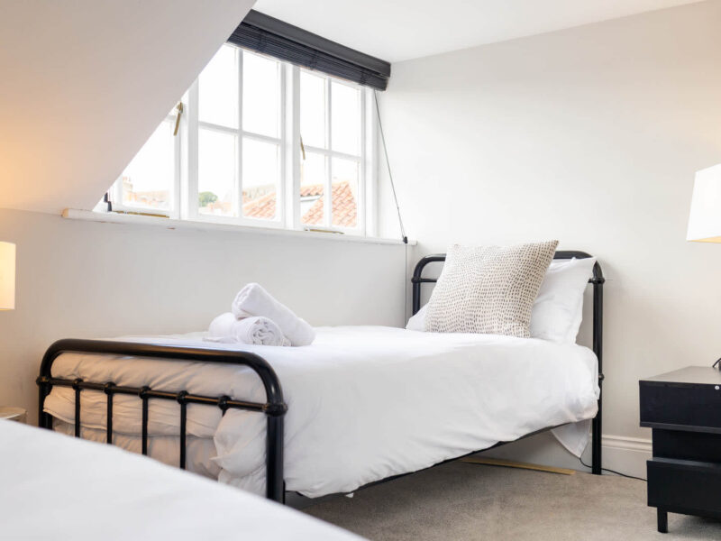 Twin beds with white linens in a bright room at Ocean Pearl holiday let.