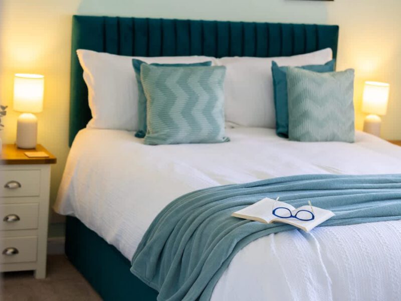 Comfortable bedroom with teal headboard at Coastal Village Hideaway.