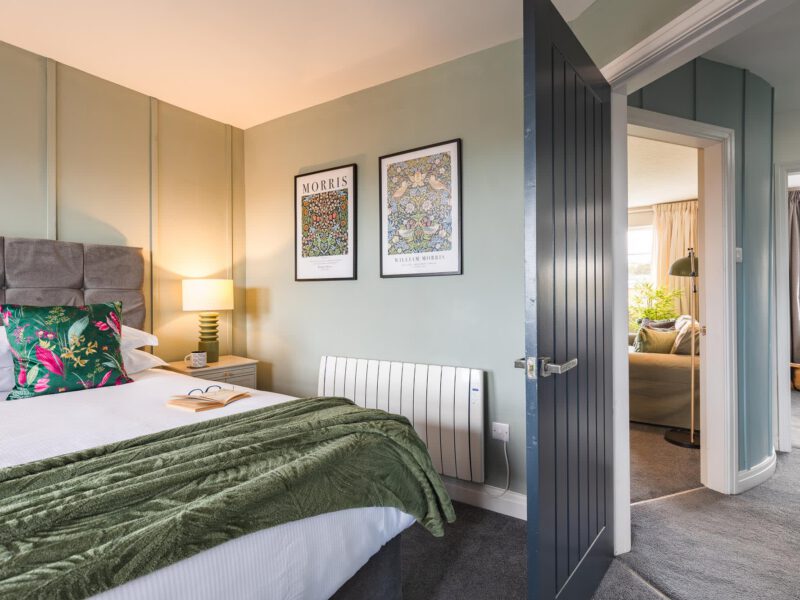 Penthouse Suite bedroom with William Morris art and plush green throw.