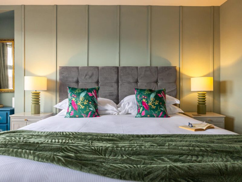 Penthouse Suite bedroom with plush green throw and tropical accent pillows.