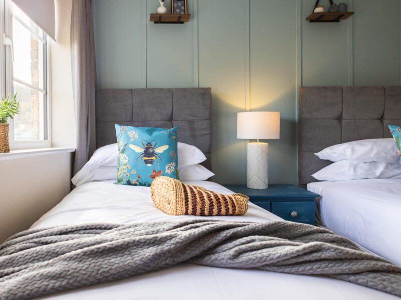 Two beds in the Penthouse Suite with bee-themed decor and cozy throws.