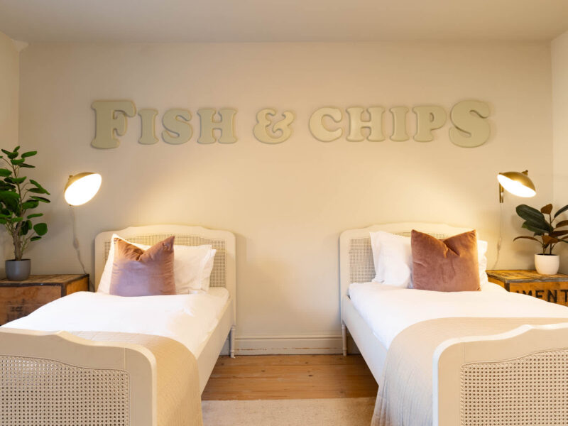 Twin beds in a dog-friendly Old Town House with "Fish & Chips" wall art.