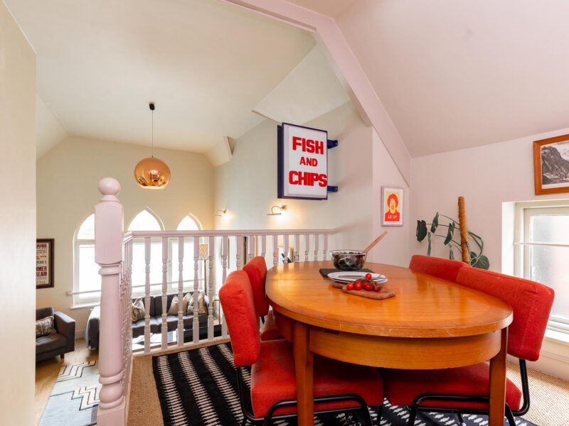 Dining area with stylish red chairs at The Loft by the Bay holiday let.