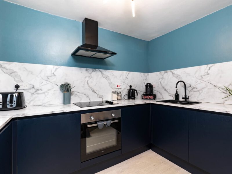 Modern kitchen with navy cabinets and marble backsplash at Old Town House.