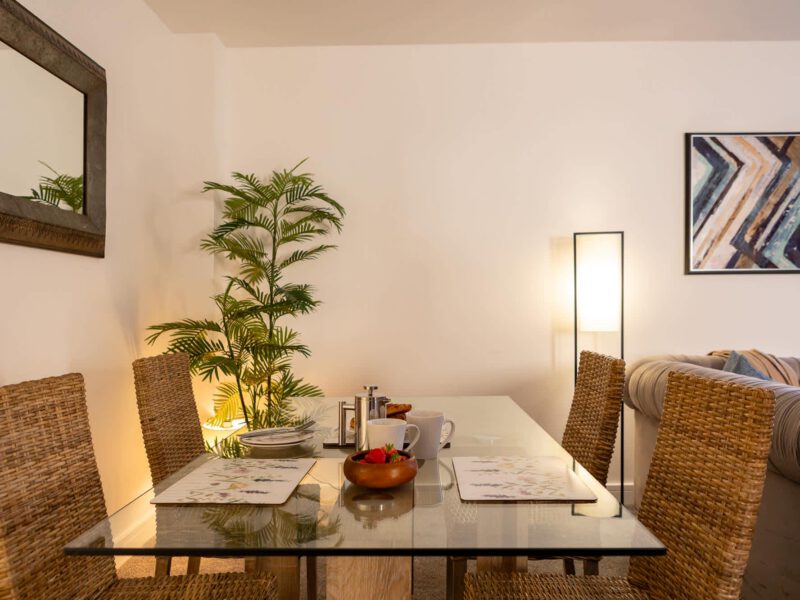 Dining area with glass table and wicker chairs at Welton View Escape.