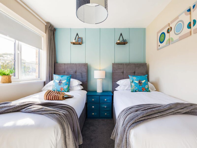 Twin beds with bee-themed pillows in the Penthouse Suite, a quiet central escape.