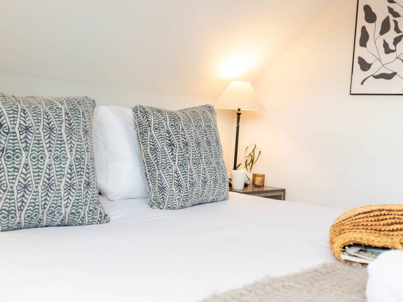 Comfortable bed with patterned pillows in Ocean Pearl holiday let.