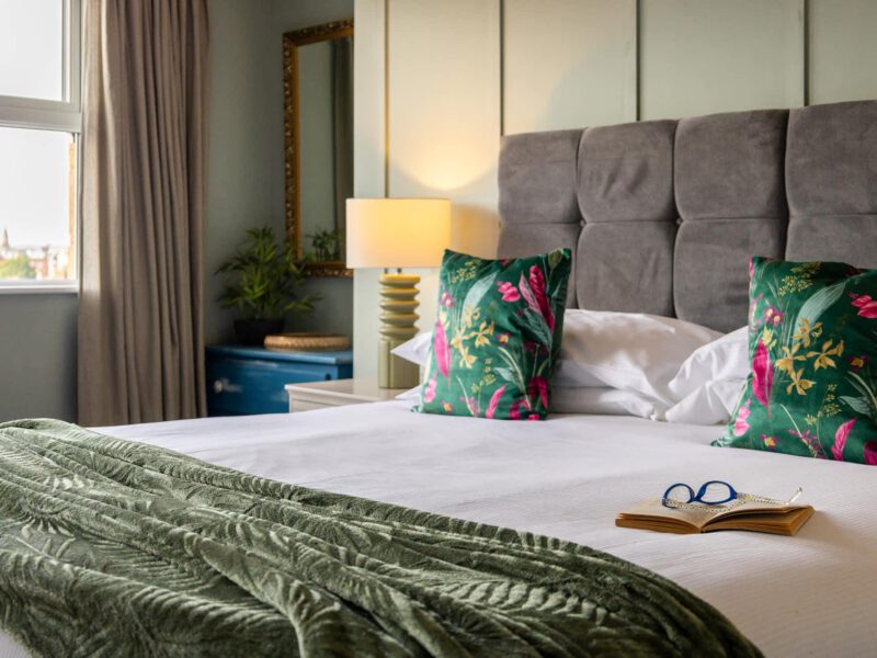 Penthouse Suite bedroom with plush throw and tropical cushions.