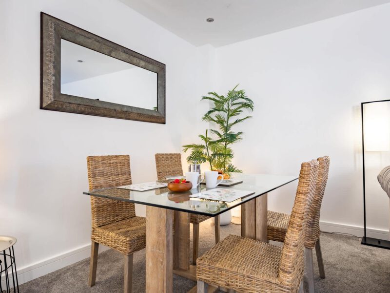 Dining area with glass table and wicker chairs at Welton View Escape.