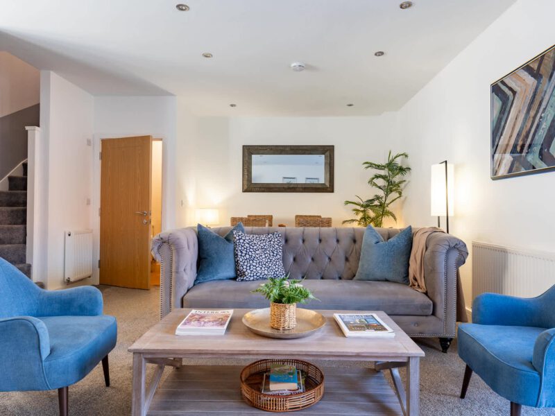 Comfortable living area with blue armchairs and grey sofa at Welton View Escape.