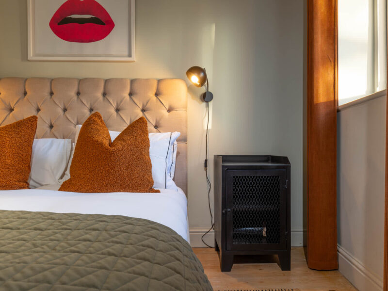 Stylish bedroom with plush headboard and orange cushions at Old Town House.