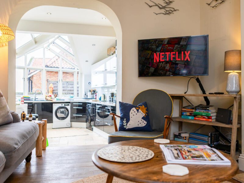 Living area with Netflix TV and modern kitchen at Harbour View House.