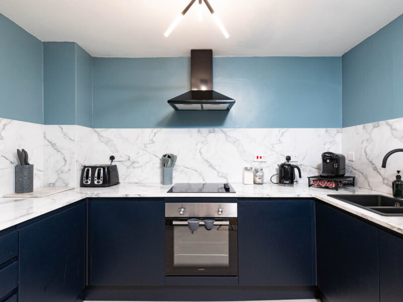 Modern kitchen with dark blue cabinets and marble countertops at Old Town House.