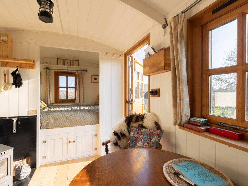 Cozy interior of Plank Bridge shepherds hut with bed and seating area.