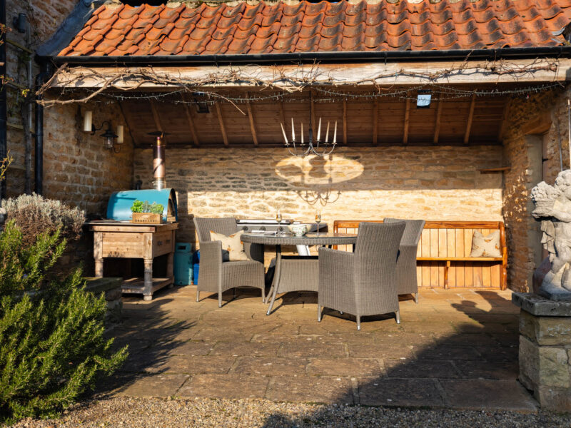 Outdoor dining area with pizza oven at East Wing holiday let.