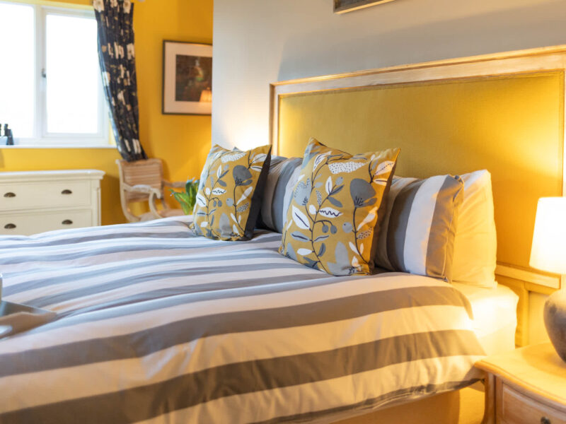 Comfortable bedroom with striped bedding at East Wing holiday let.