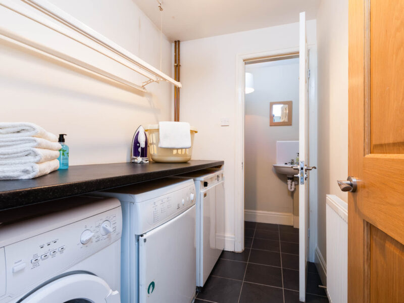 Laundry room with washer, dryer, and ironing facilities at East Wing holiday let.