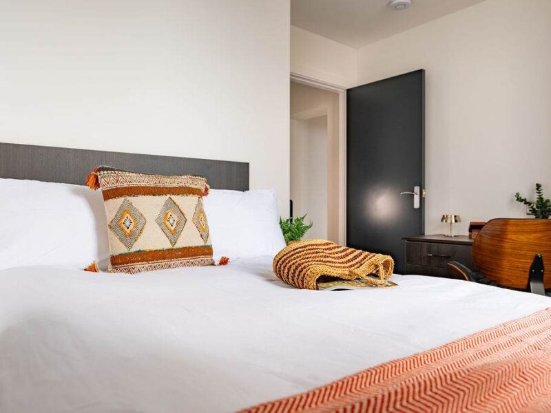 Comfortable bed with decorative pillows at Albemarle Chambers central retreat.