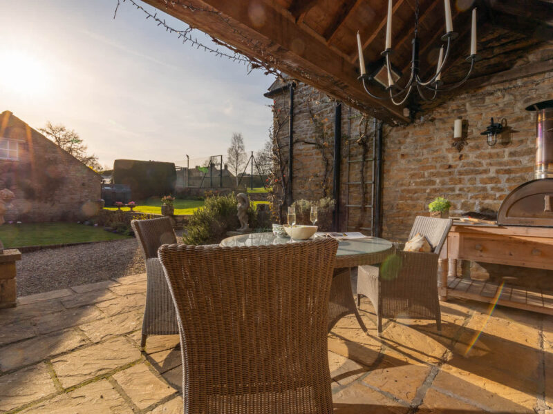 East Wing patio with pizza oven and tennis court views.
