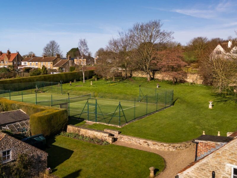 Tennis court and gardens at East Wing holiday let, with countryside views.