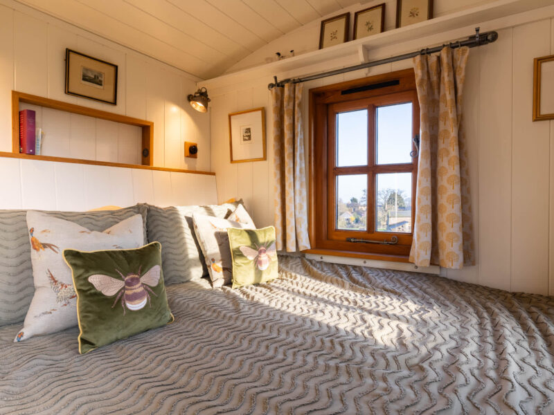 Cozy bed with bee cushions in Plank Bridge shepherds hut, sleeps 2.