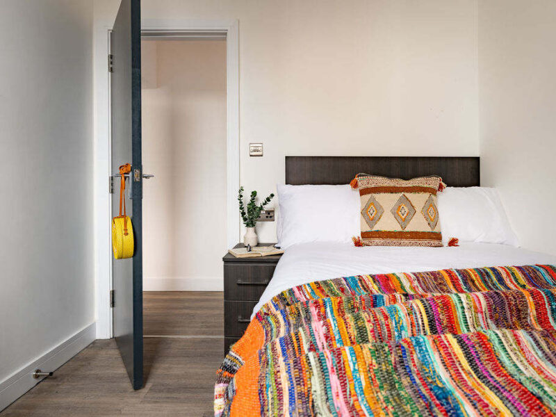 Cozy bedroom with colorful throw at Albemarle Chambers central retreat.