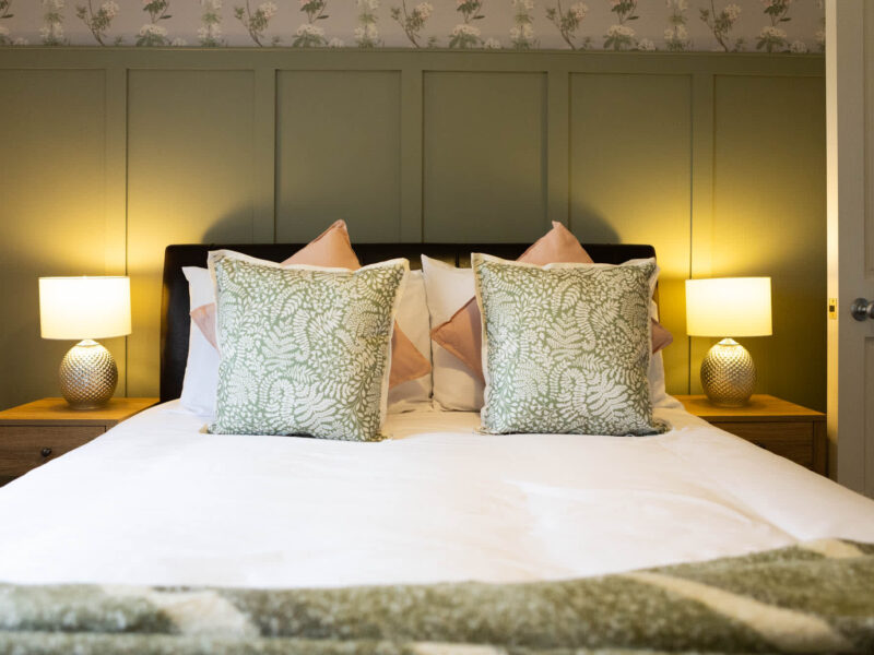Comfortable bedroom with botanical print cushions at Malton Luxury Retreat.